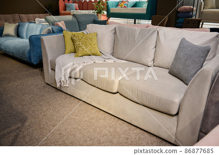 Comfortable upholstered settee with colored stylish green olive pillows displayed for sale in the furniture store showroom. Exhibition of upholstered furniture. Comfortable upholstered settee with colored stylish green olive pillows displayed for sale in the furniture store showroom. Exhibition of upholstered furniture. 86877685