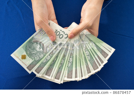 In his hands he holds a fan of banknotes with a face value of one hundred Polish zlotys. Many bills to have a choice. 86878457