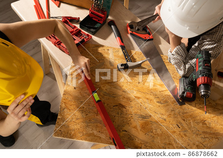 The girls check with a spirit level whether the surface of the table on which they are working maintains the acceptable deviation parameters from the level. 86878662