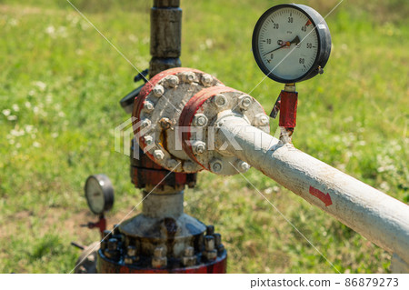Pressure gauges on pipes through which oil is pumped. There is rust and traces of oil products on the pipes. Dirty extraction of black gold from the well. Pollution of the environment Pressure gauges on pipes through which oil is pumped. There is rust and traces of oil products on the pipes. Dirty extraction of black gold from the well. Pollution of the environment 86879273