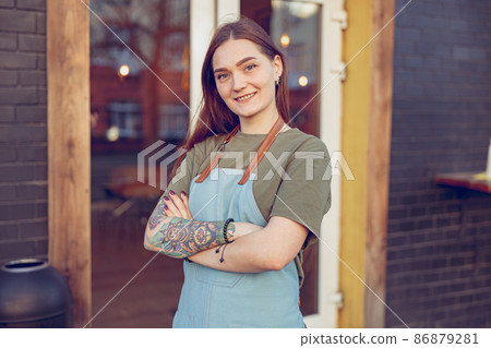 Cheerful female barista standing outside coffee shop 86879281