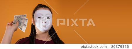 In a panoramic frame, an anonymous woman stands and draws in her hand with paper banknotes of one hundred Polish zlotys. No face because there's a mask on it. In a panoramic frame, an anonymous woman stands and draws in her hand with paper banknotes of one hundred Polish zlotys. No face because there's a mask on it. 86879526