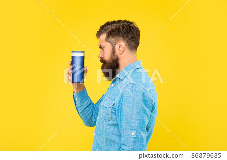 profile of brutal bearded man hold hair conditioner bottle on yellow background, haircare 86879685