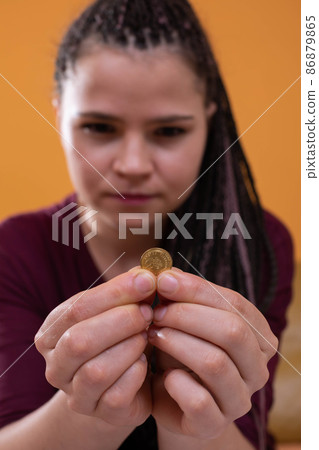 Teenagers were left with the last pennies of spending savings until the end of a long month. The girl holds a dime in her fingers, hoping for a better future 86879865