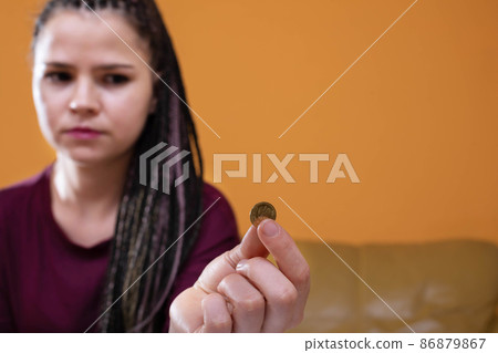 Teenagers were left with the last pennies of spending savings until the end of a long month. The girl holds a dime in her fingers, hoping for a better future 86879867