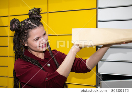 A young girl looks with interest and joy at the package that has just arrived. She received an unexpected mail. A young girl looks with interest and joy at the package that has just arrived. She received an unexpected mail. 86880173