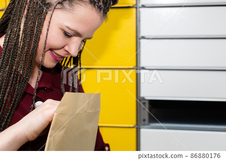 A young girl looks with interest and joy at the package that has just arrived. She received an unexpected mail. A young girl looks with interest and joy at the package that has just arrived. She received an unexpected mail. 86880176