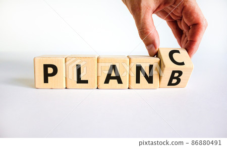 Plan B or C symbol. Businessman turns a wooden cube and changes words Plan B to Plan C. Beautiful white table, white background, copy space. Business and Plan B or C planning concept. 86880491