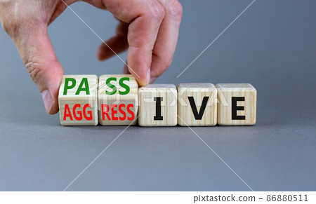 Passive or aggressive symbol. Businessman turns wooden cubes and changes the word passive to aggressive. Beautiful grey background, copy space. Business, psychological passive aggressive concept. Passive or aggressive symbol. Businessman turns wooden cubes and changes the word passive to aggressive. Beautiful grey background, copy space. Business, psychological passive aggressive concept. 86880511