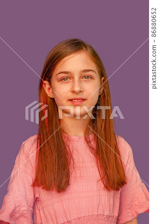 Cute girl with long hair on a purple background in a pink dress. Portrait of a teenagers girl. Cute girl with long hair on a purple background in a pink dress. Portrait of a teenagers girl. 86880652