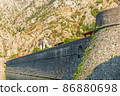 Detail of the ancient stone wall of the Gurdic Gate near the pond water in the old town of Kotor, Montenegro 86880698
