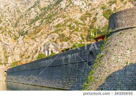 Detail of the ancient stone wall of the Gurdic Gate near the pond water in the old town of Kotor, Montenegro Detail of the ancient stone wall of the Gurdic Gate near the pond water in the old town of Kotor, Montenegro 86880698