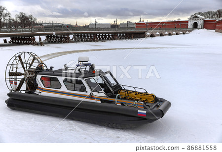 Amphibious boat of the search and rescue service of St. Petersburg on the river ice against the background of the Peter and Paul Fortress. Amphibious boat of the search and rescue service of St. Petersburg on the river ice against the background of the Peter and Paul Fortress. 86881558