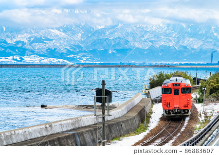 Toyama Prefecture Winter Himi Line (Amaharashi Coast) -Diesel train running with the Tateyama mountain range in the background- Toyama Prefecture Winter Himi Line (Amaharashi Coast) -Diesel train running with the Tateyama mountain range in the background- 86883607