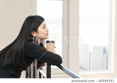 A business woman relaxing with her elbows on the railing and a coffee cup 86884541