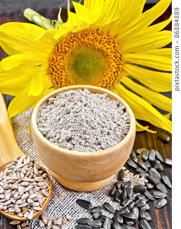 Flour sunflower in bowl with flower on dark board Flour sunflower in bowl with flower on dark board 86884889