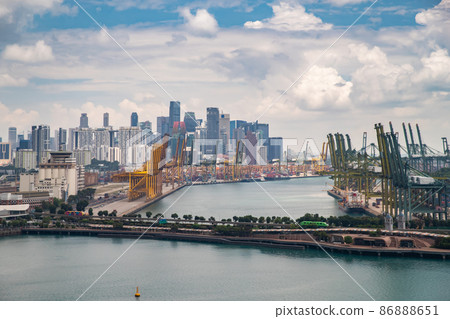 The huge busiest logistic port in Singapore, plenty of cranes to move containers, huge cargo ships in the background, skyscrapers on background The huge busiest logistic port in Singapore, plenty of cranes to move containers, huge cargo ships in the background, skyscrapers on background 86888651