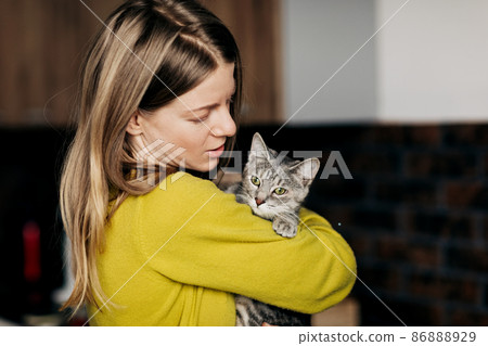 Young woman in home clothes hugging her cat at home 86888929