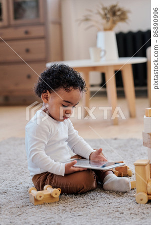 Curly black boy watching cartoons on tablet Curly black boy watching cartoons on tablet 86890996
