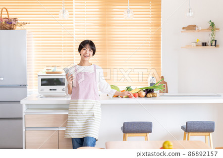 操作智能手機的一個少婦在廚房裡 86892157