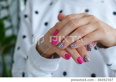 Manicured female hands with stylish pink nails and design. Trendy modern design manicure. Gel nails. Skin care. Beauty treatment. Nail care. Trendy colors 86892567