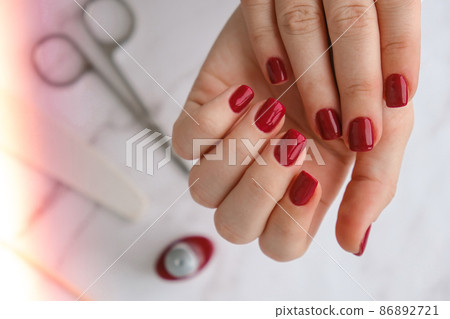 Stylish red female nails. Modern Beautiful manicure. Autumn winter nail design concept of beauty treatment. Gel nails. Skin care. Stylish red female nails. Modern Beautiful manicure. Autumn winter nail design concept of beauty treatment. Gel nails. Skin care. 86892721