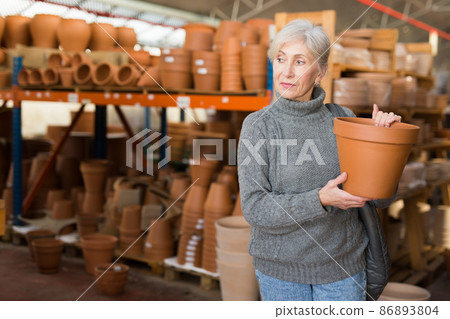 Elderly woman looking for flower pots in hypermarket Elderly woman looking for flower pots in hypermarket 86893804