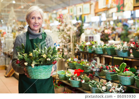 Mature woman decorative goods store worker with christmas decoration 86893930