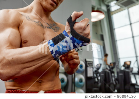A beautiful athlete wraps his hands on sports bandages for boxing. Preparation before workout. The mood before the fight. A beautiful athlete wraps his hands on sports bandages for boxing. Preparation before workout. The mood before the fight. 86894150
