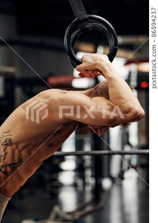 Muscle-up exercise young man doing intense cross fit workout at the gym on gymnastic rings. Muscle-up exercise young man doing intense cross fit workout at the gym on gymnastic rings. 86894237