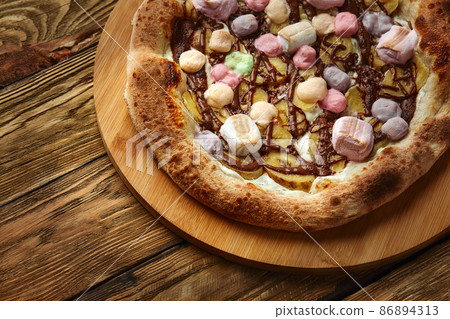 Whole sweet pizza served with marshmallows and candies Whole sweet pizza served with marshmallows and candies 86894313