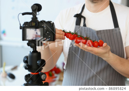 Vlogger chef showing ripe tomatoes ingredient, man in apron recording red vegetable 86895824