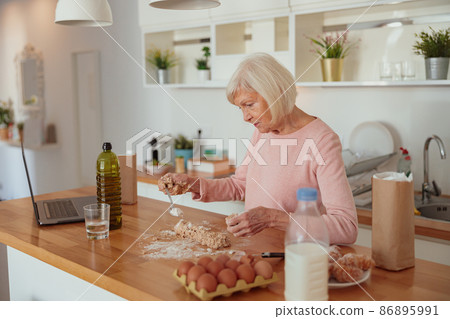 Aged housewife cooking in kitchen at home 86895991