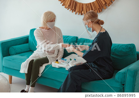 Senior woman visited by district nurse at home Senior woman visited by district nurse at home 86895995