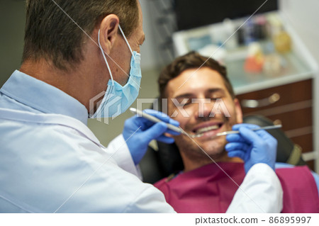 Professional dentist examining a young brunette man Professional dentist examining a young brunette man 86895997