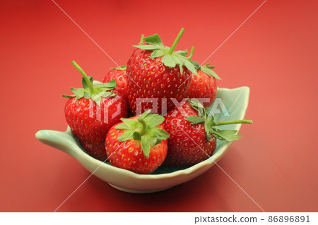 Red strawberries in a bowl. on red background 86896891