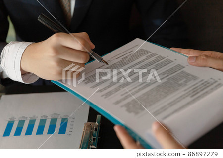 Businessman concept the marketing analyst checking the data on the paper to compare with the information in the graphic for analysis 86897279