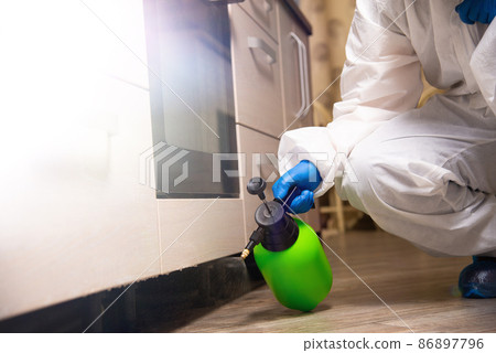 Spray gun with pesticides close-up. An exterminator in work clothes sprays pesticides from a spray bottle. Fight against insects in apartments and houses. Disinsection of premises 86897796