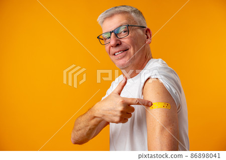 Senior man against yellow background recieved corona virus vaccination Senior man against yellow background recieved corona virus vaccination 86898041