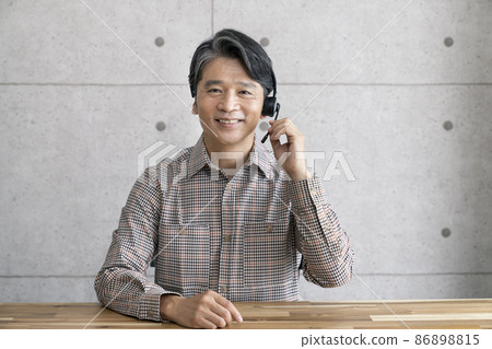 一名 50 多歲的男子戴著耳機看著相機 一名 50 多歲的男子戴著耳機看著相機 86898815