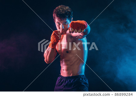 Front view of aggressive boxer who training and practicing jab on smoke background. Sport concept Front view of aggressive boxer who training and practicing jab on smoke background. Sport concept 86899284