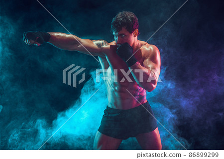 Half length of athlete boxer who training and practicing jab on smoke background. Sport concept 86899299