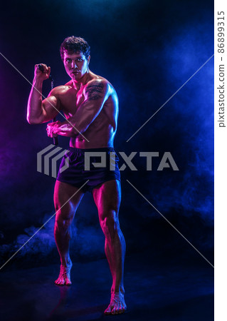 Full size of muscular man who trains with nunchaku while isolated on black background. Sport concept 86899315