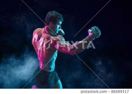 Side view of Muscular fighter who delivering hit with chain on smoke background. mixed media 86899317