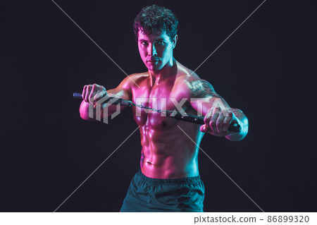 Portrait of athlete man who holds nunchaku while isolated on black background. Sport concept 86899320