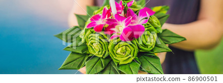 BANNER, LONG FORMAT A female tourist holds the Loy Krathong in her hands and is about to launch it into the water. Loy Krathong festival, People buy flowers and candle to light and float on water to 86900501