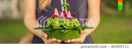BANNER, LONG FORMAT A female tourist holds the Loy Krathong in her hands and is about to launch it into the water. Loy Krathong festival, People buy flowers and candle to light and float on water to 86900511