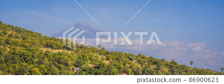 Aerial view of Amed beach in Bali, Indonesia. Traditional fishing boats called jukung on the black sand beach and Mount Agung volcano in the background, partially covered by clouds BANNER, LONG FORMAT 86900623