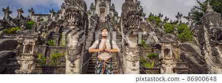 Young man tourist on background ofThree stone ladders in beautiful Pura Lempuyang Luhur temple. Summer landscape with stairs to temple. Paduraksa portals marking entrance to middle sanctum jaba tengah 86900648