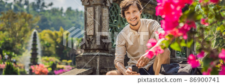 Young man tourist in Taman Tirtagangga, Water palace, Water park, Bali Indonesia BANNER, LONG FORMAT Young man tourist in Taman Tirtagangga, Water palace, Water park, Bali Indonesia BANNER, LONG FORMAT 86900741